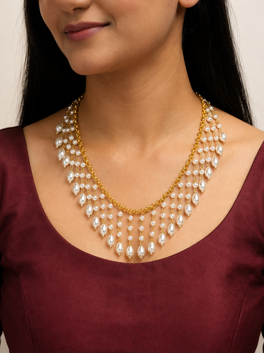 Model wearing a gold-tone cascade necklace with white pearl drops