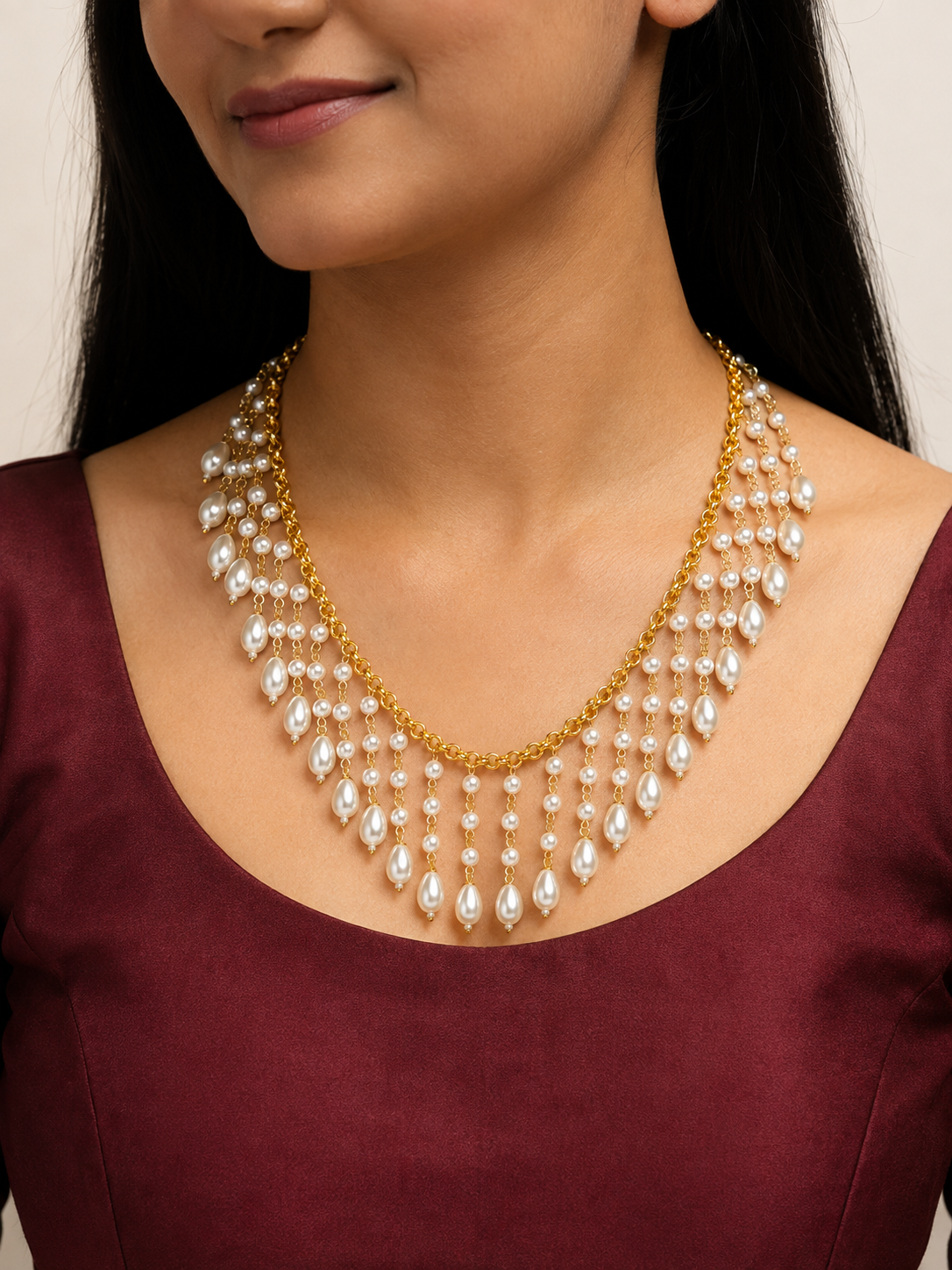 Model wearing a gold-tone cascade necklace with white pearl drops