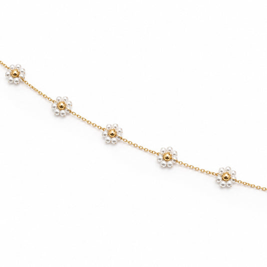 Close-up of white pearl flower motifs with polished gold-tone bead centres