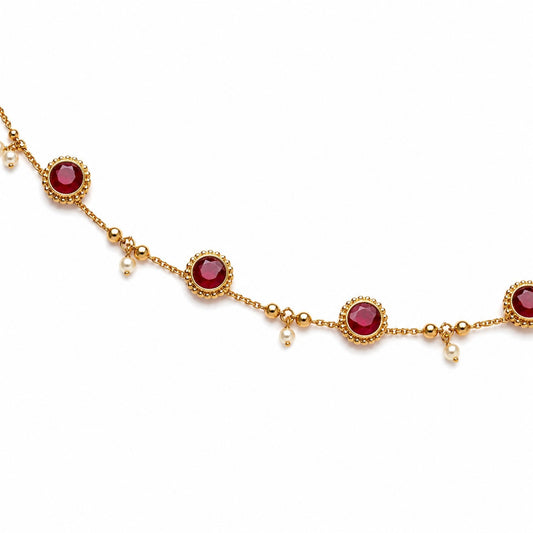 Close-up of gold-tone hip chain with round ruby-coloured stones, gold beads and pearl drops