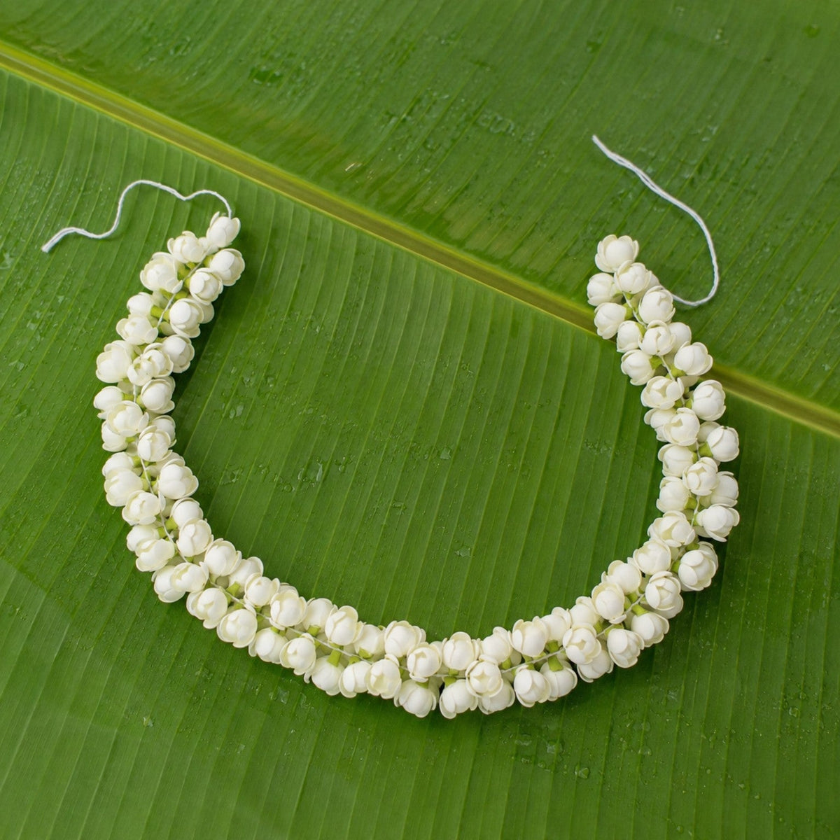 Artificial jasmine hair garland arranged on a green banana leaf
