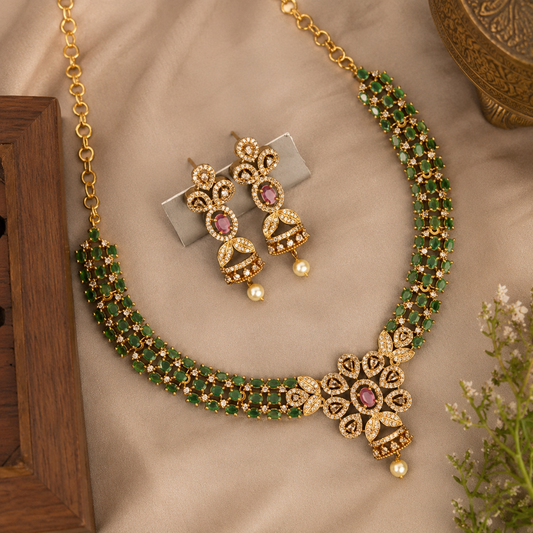 Gold and green beaded necklace set with matching earrings, displayed on a beige fabric background with decorative props.