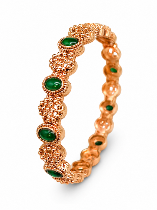 A rose gold bangle bracelet featuring textured pavé and milgrain details, accented with oval green stone inlays, shown on a clean white background.