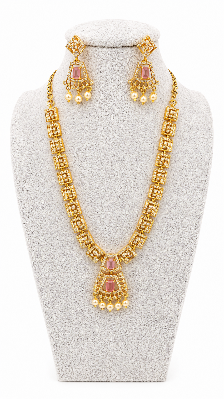 Gold-plated Indian jewelry set featuring a necklace and matching earrings with pink stones and pearl-like accents, displayed on a white textured bust.