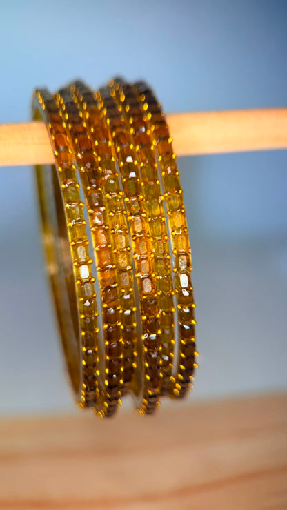 Belumiee Navrang Sparkle Glass Bangles Set featuring amber gold-colored bangles with shimmering glass finish.