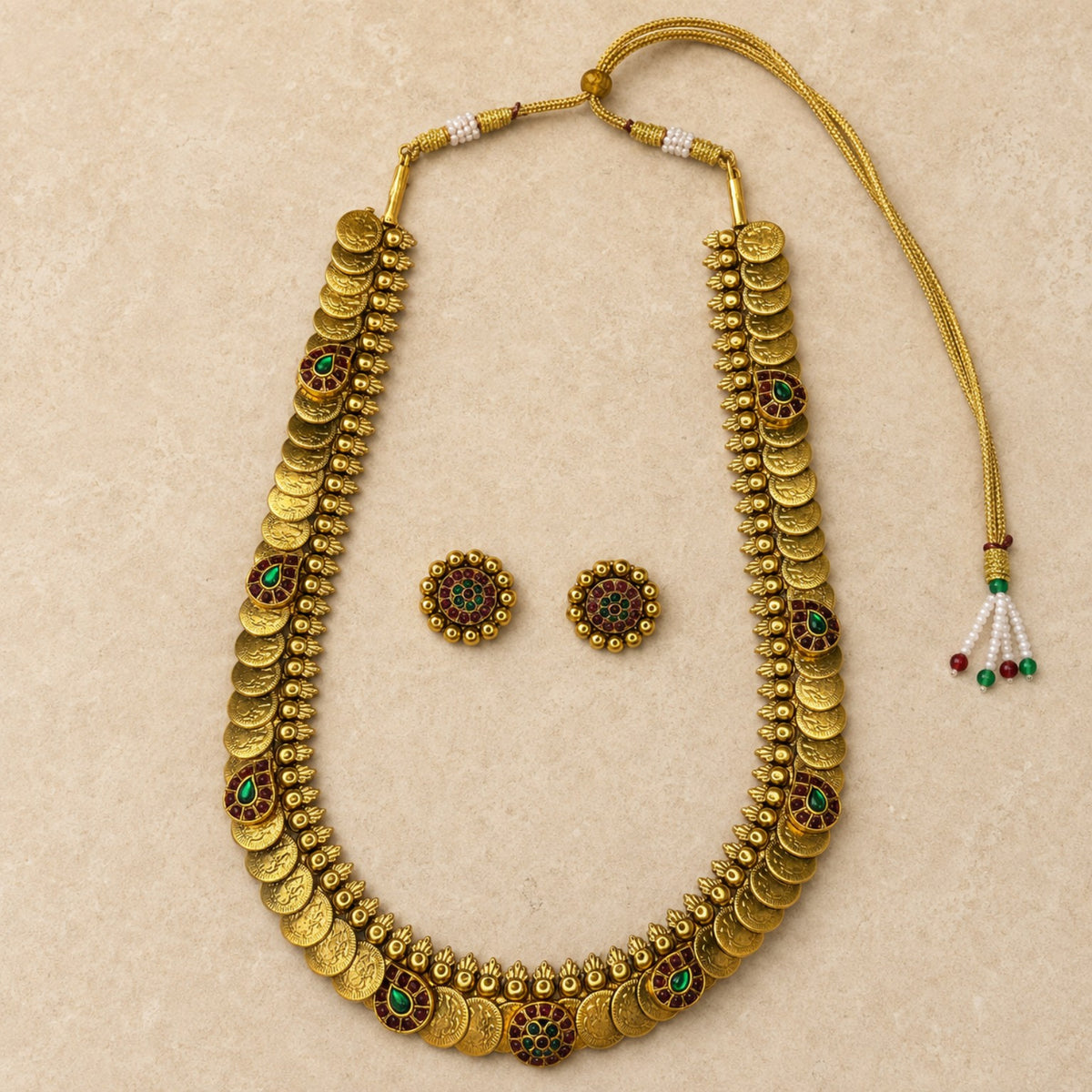 Antique gold coin Kasu Mala long Haram necklace and matching earrings set with ruby and green accents, traditional Indian jewelry.