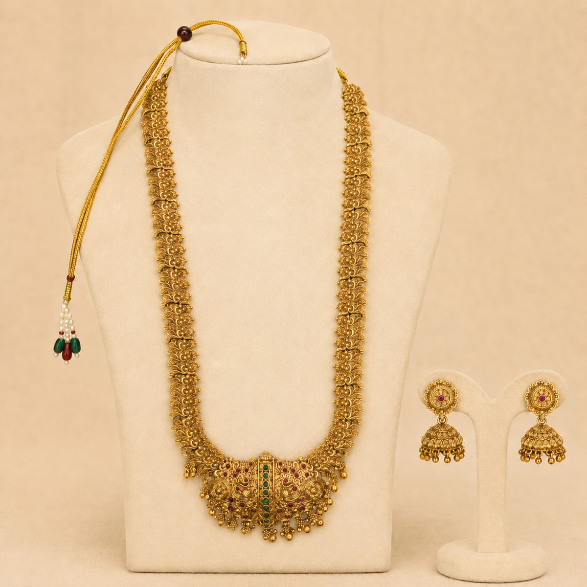 Antique gold peacock temple long haram necklace set with ruby and green accents, paired with matching jhumka earrings, traditional jewelry.