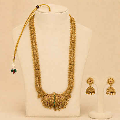 Antique gold peacock temple long haram necklace set with ruby and green accents, paired with matching jhumka earrings, traditional jewelry.