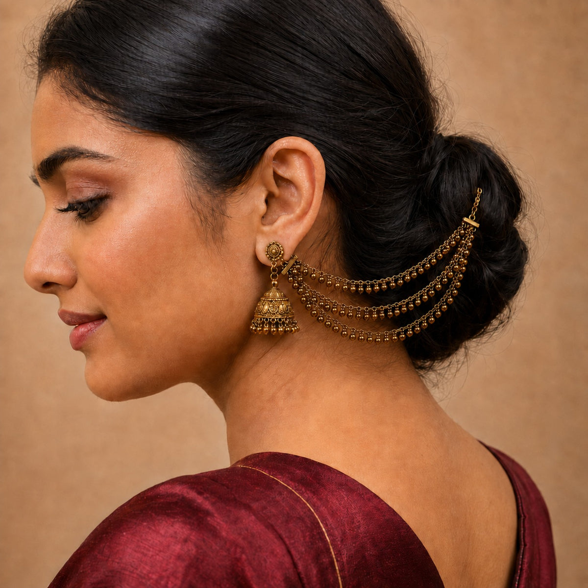 Model wearing one side of an antique gold triple-layer gold bead fringe ear chain pair