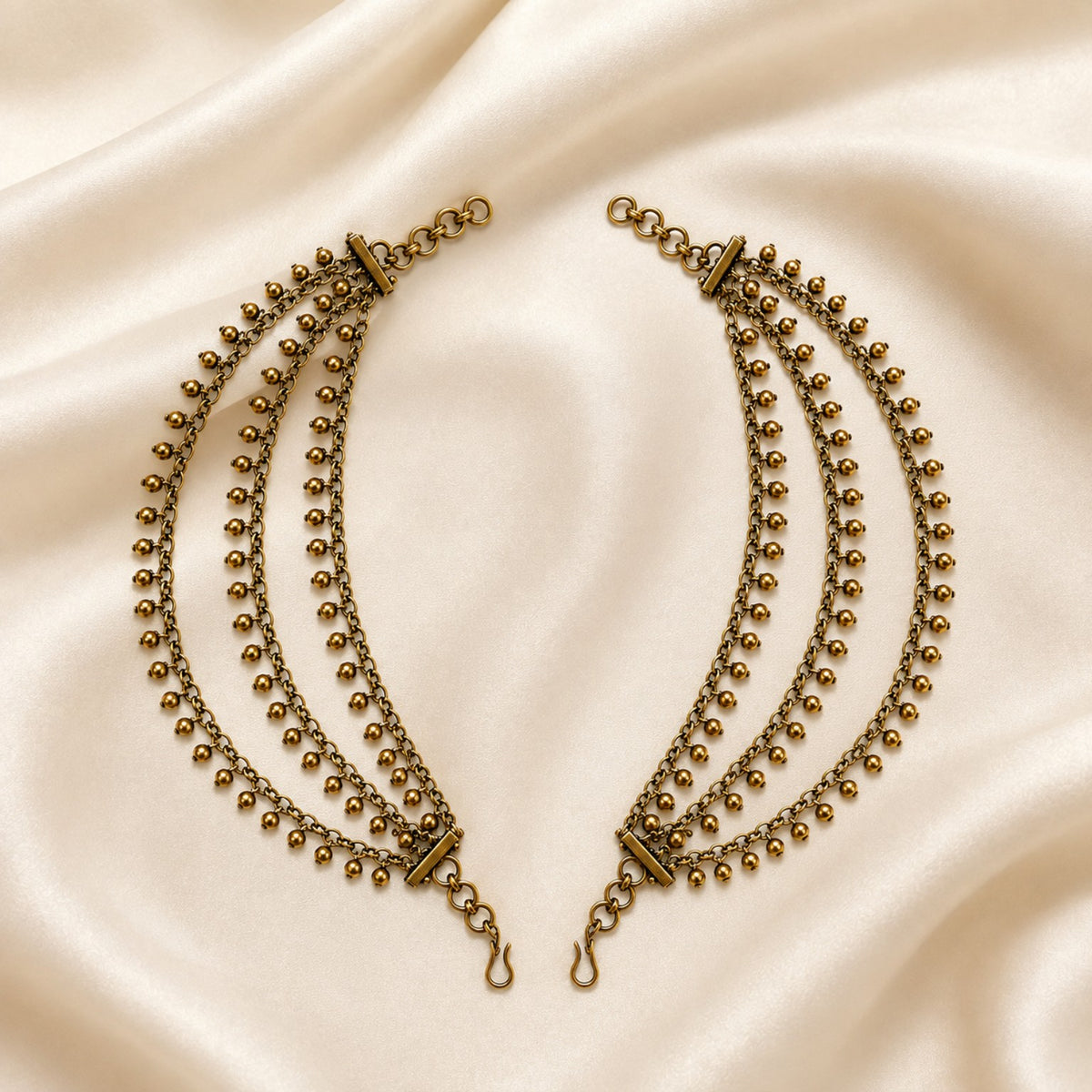 Antique gold triple-layer gold bead fringe ear chain pair displayed on satin