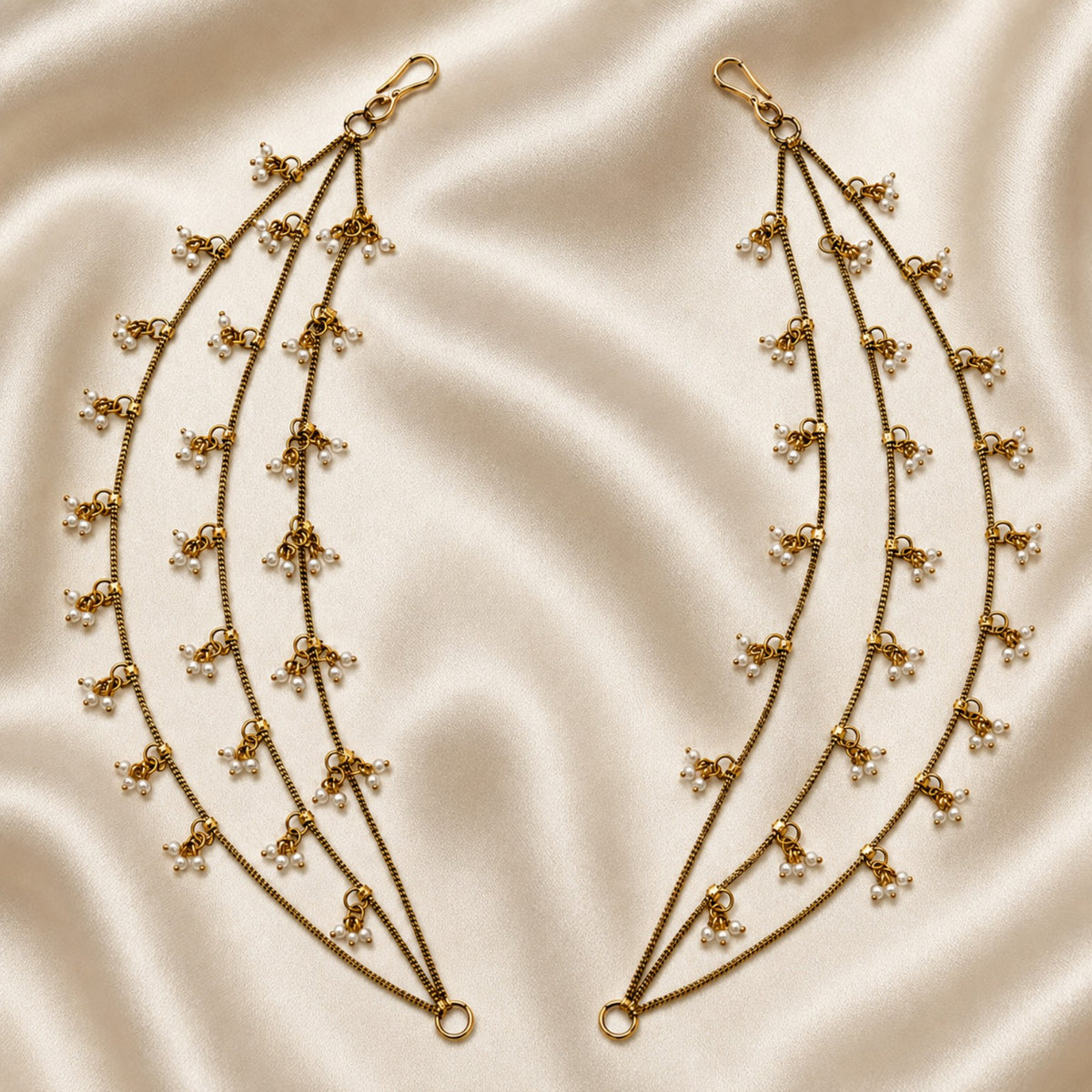 Antique gold triple-layer pearl cluster ear chain pair displayed on satin