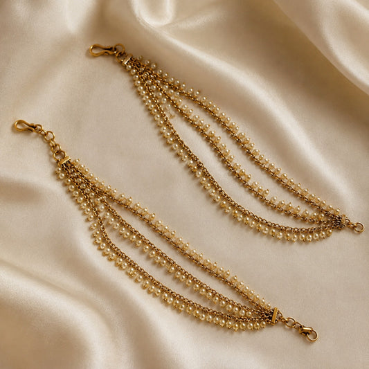 Antique gold triple-layer pearl fringe ear chain pair displayed on satin