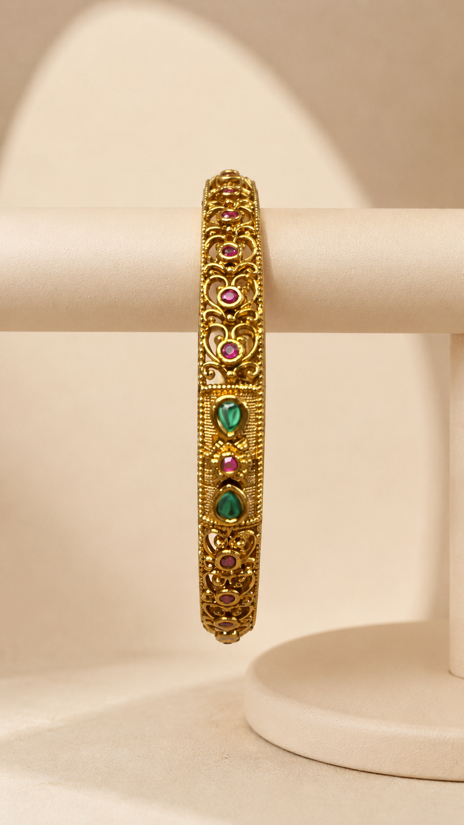 Antique ruby and emerald filigree bangle by Belumiee, featuring intricate design and vibrant gemstones on a polished metal bracelet.