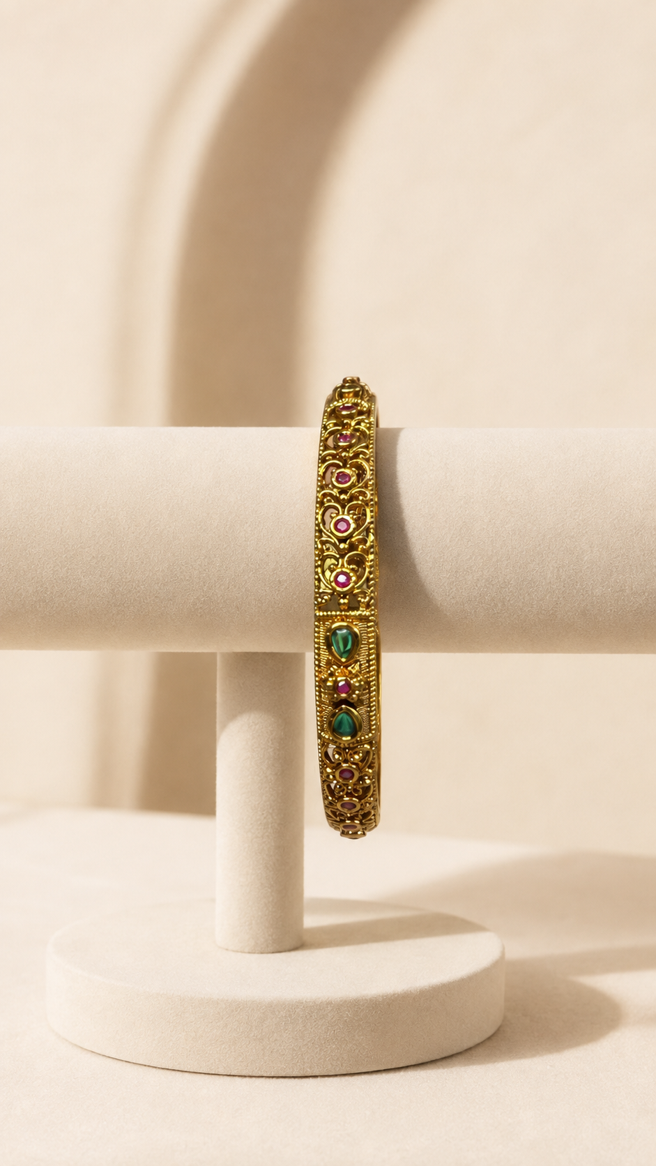 Antique ruby and emerald filigree bangle by Belumiee, showcasing intricate goldwork with vibrant red and green gemstones.