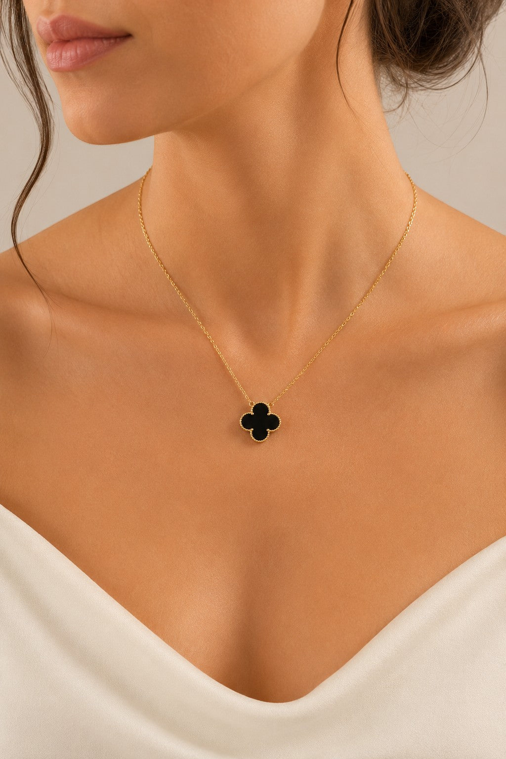 Belumiee sterling silver clover pendant necklace with black enamel on a gold chain worn by a woman.