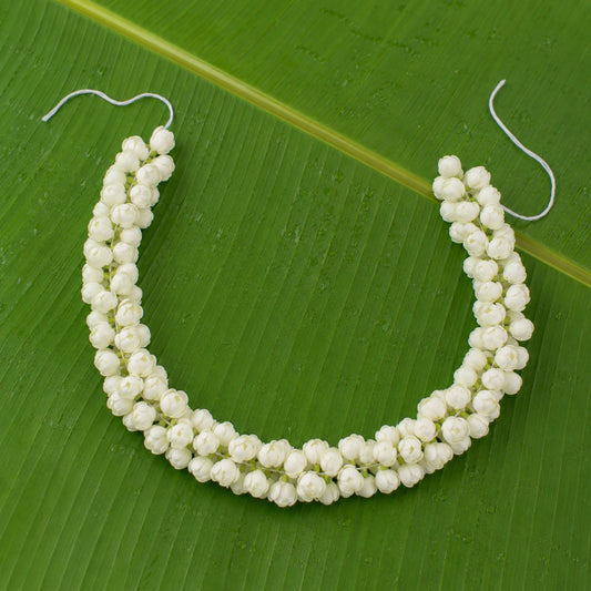 Double-layer artificial jasmine hair garland arranged on a green banana leaf