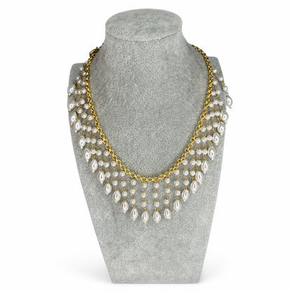 Gold-tone pearl cascade fashion necklace on a grey display bust