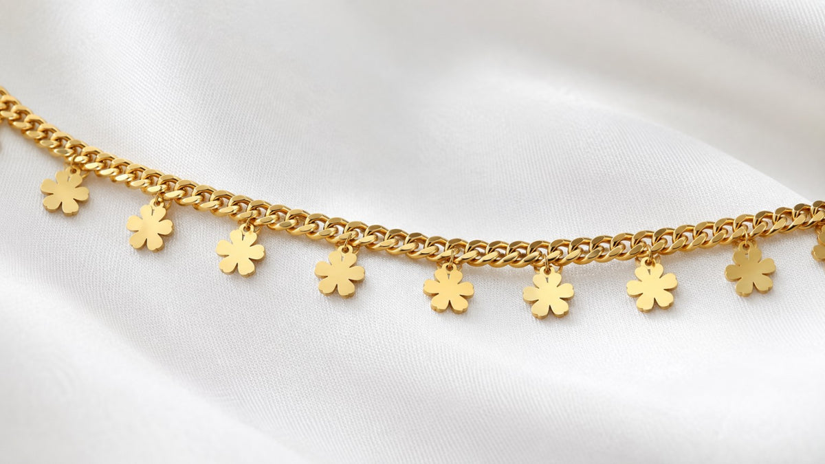 Close-up of polished flower charms on a gold-tone curb-chain hip chain