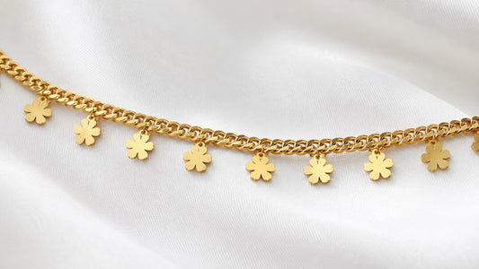 Close-up of polished flower charms on a gold-tone curb-chain hip chain