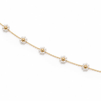 Close-up of white pearl flower motifs with polished gold-tone bead centres