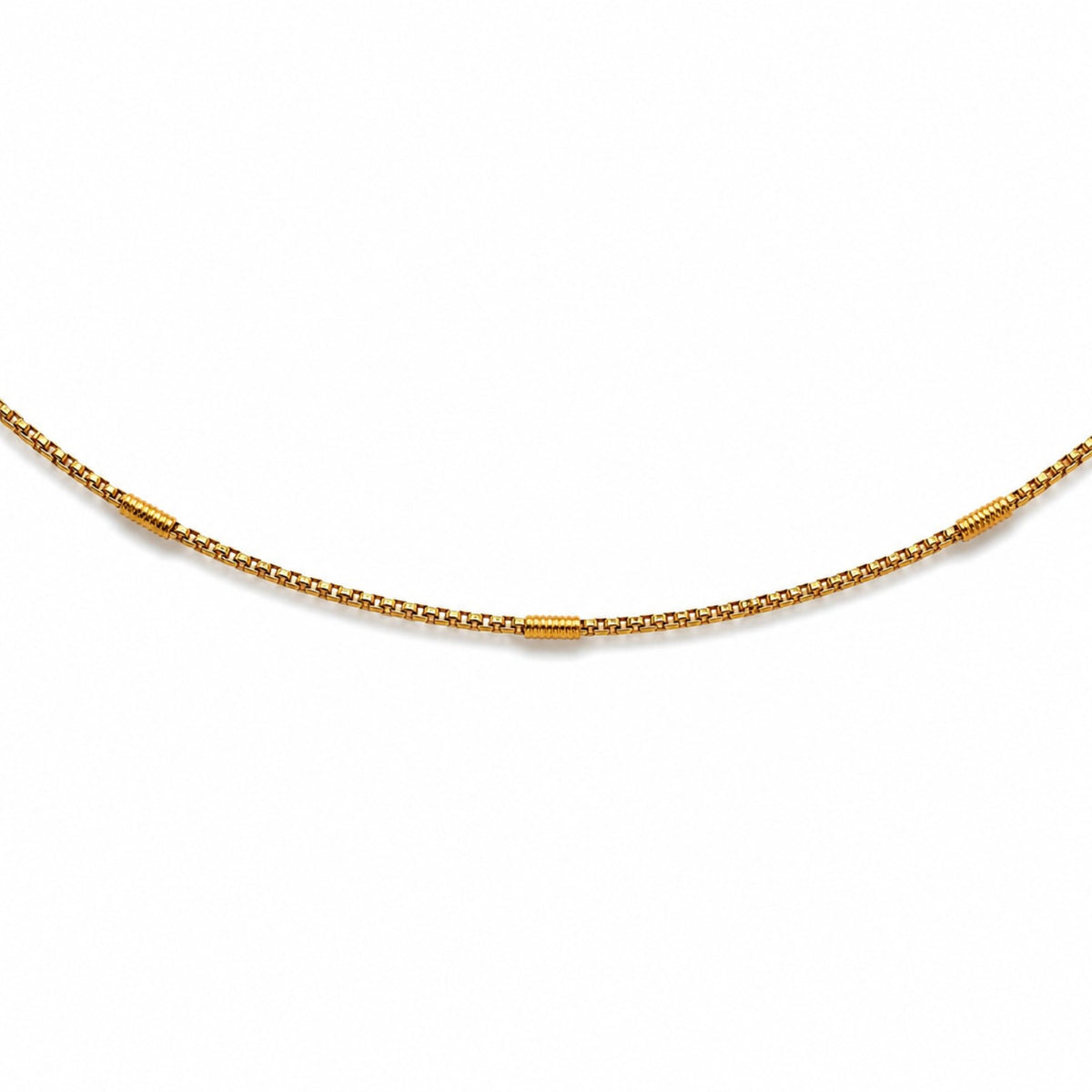 Close-up of gold-tone hip chain with evenly spaced textured barrel accents