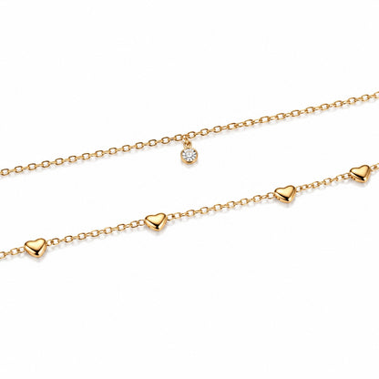 Close-up of polished heart stations and clear crystal-style accent on gold-tone hip chain