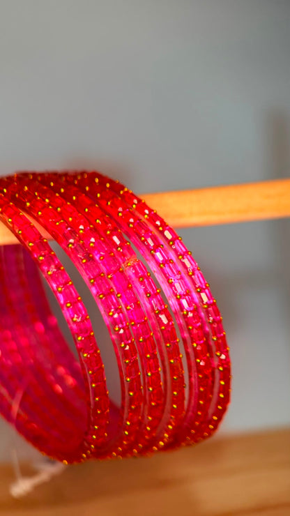Belumiee Navrang Sparkle Glass Bangles Set featuring light ruby-colored bangles with sparkling glass accents.