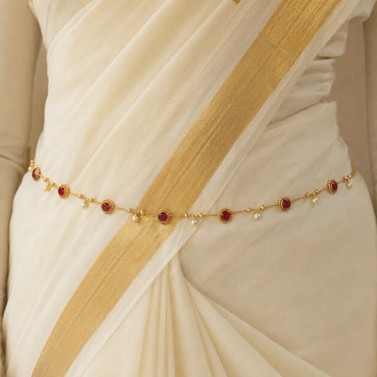 Model wearing round ruby stone and pearl drop gold-tone hip chain with Kerala saree