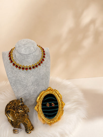 Traditional gold-tone necklace set with vibrant ruby-red gemstones, featuring matching earrings in a classic design.