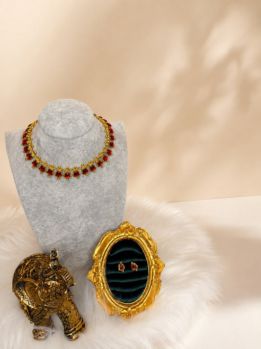 Traditional gold-tone necklace set with vibrant ruby-red gemstones, featuring matching earrings in a classic design.